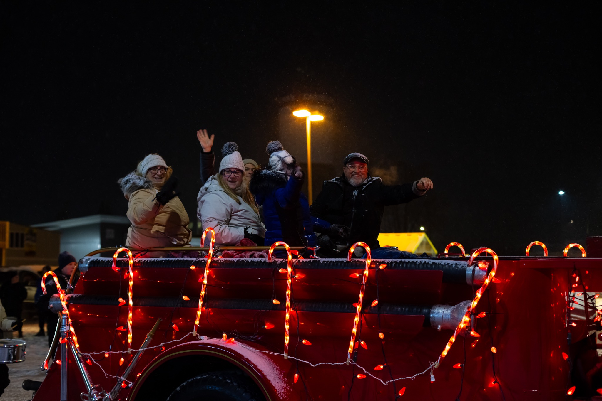 From left to right: Casselman Mayor Geneviève Lajoie, Councillor Anik Charron, Councillor Sylvain Cléroux (far back, waving his hand), and Councillor Paul Groulx greet spectators while taking part in the illuminated Christmas parade during the Casselman Christmas Festival.